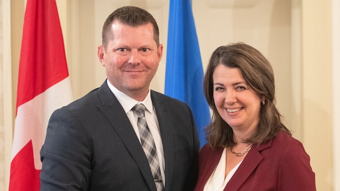 RJ Sigurdson et Danielle Smith posent devant des drapeaux.