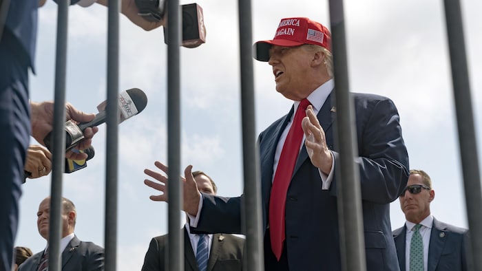 Photographié à travers des barreaux, Donald Trump s'adresse à des journalistes.