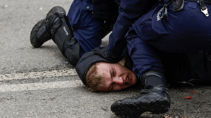 Un homme est cloué au sol par des policiers.