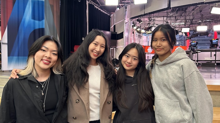 Quatre femmes sourient à la caméra. Derrière elles, un studio de télévision.