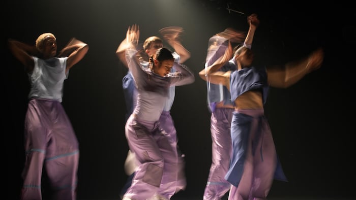 Cinq danseurs sur scène en pleine prestation.