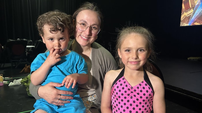Une mère souriante avec son fils sur ses genoux et sa fille à ses côtés.