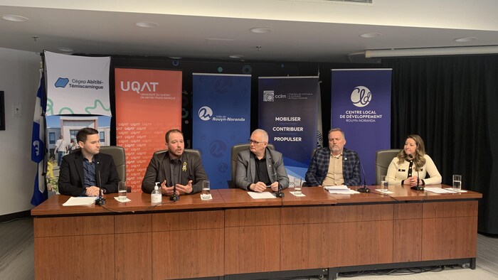 Plusieurs personnes assises derrière une table pour une conférence de presse.