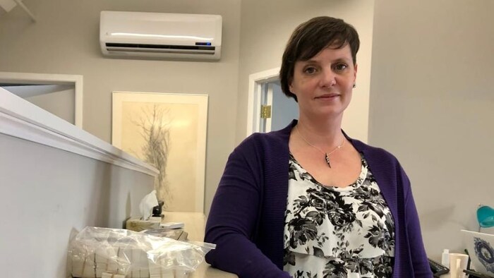 Danya O'Malley, debout un coude appuyé sur un bureau à sa droite, pose pour une photo.