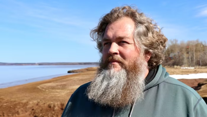 Un homme barbu se tient debout près de la rivière Avon.