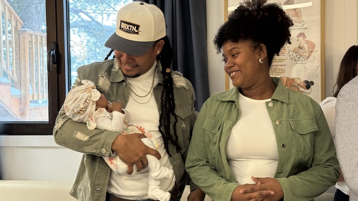 Des parents regardent leur bébé en souriant. 