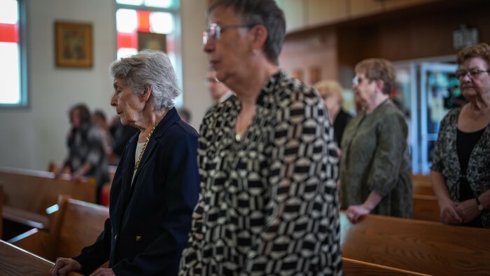 Des femmes âgées sont debout dans une église.