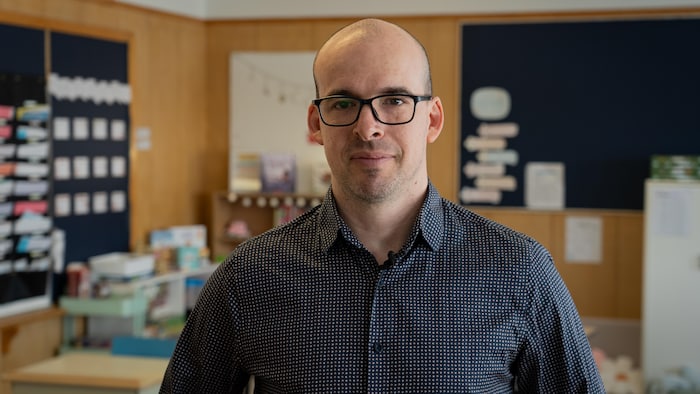 Un homme avec une chemise noir dans une classe.