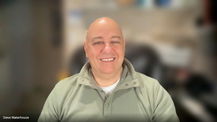 Dave Waterhouse est assis et sourit à la caméra.
