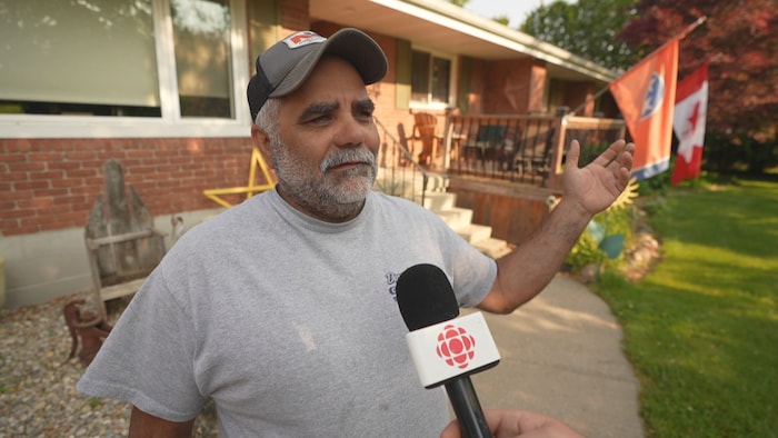 Dave Willson devant son bungalow où flotte un drapeau canadien.