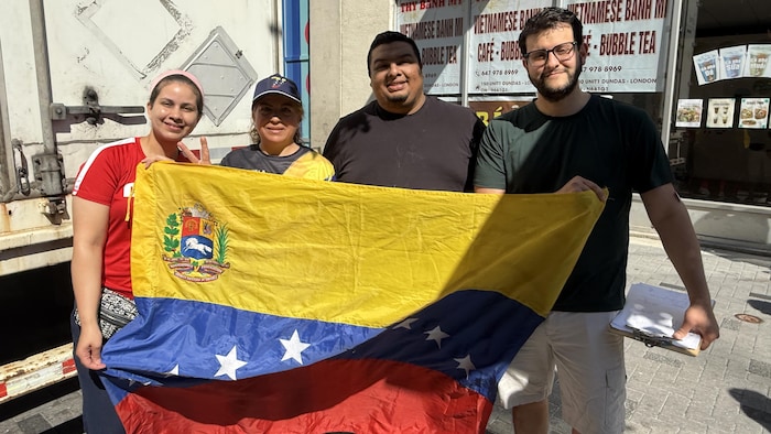 Quatre bénévoles tiennent le drapeau vénézuélien.