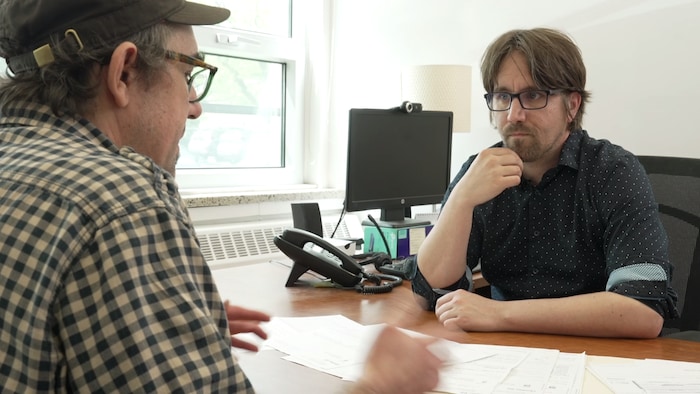 Les deux hommes discutent à son bureau.