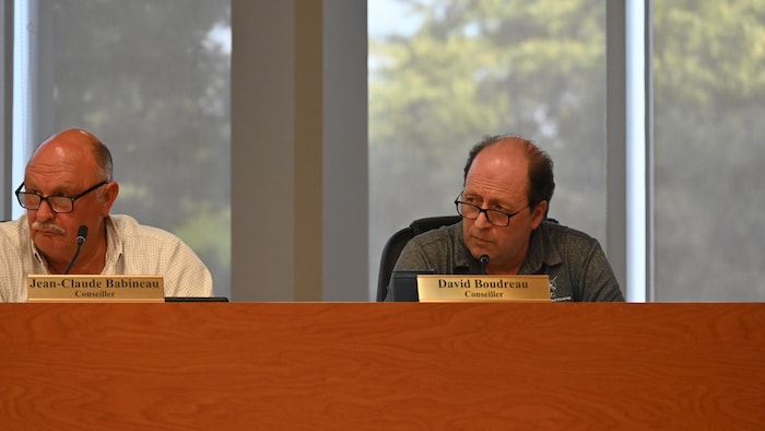 Un homme assis à la table du conseil municipal de Grand-Bouctouche. Il écoute attentivement le directeur général parler.