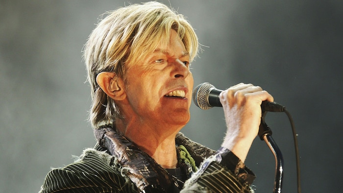 Un homme blond chante dans un micro.