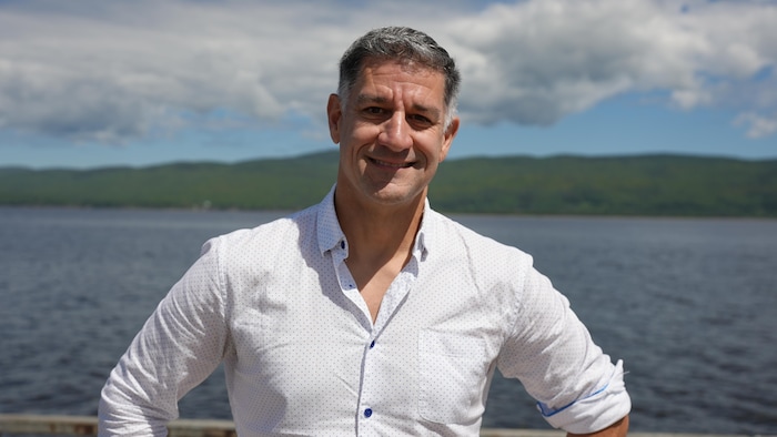David Courtemanche devant une étendue d'eau et des collines dans le fond.