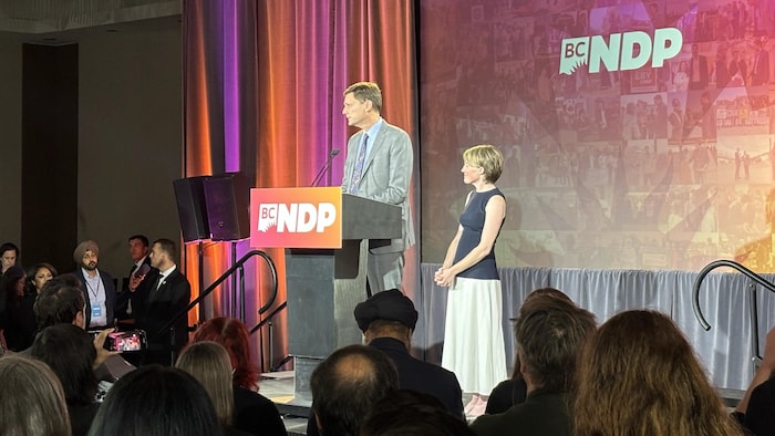 David Eby avec sa femme en train de faire un discours sur la scène du quartier général du Nouveau parti démocratique, le 24 octobre 2026.