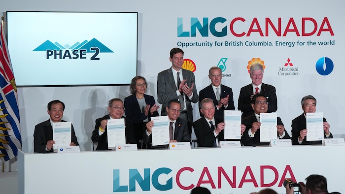 Un groupe d'hommes et de femmes d'affaires posent avec des documents lors d'un événement de LNG Canada.