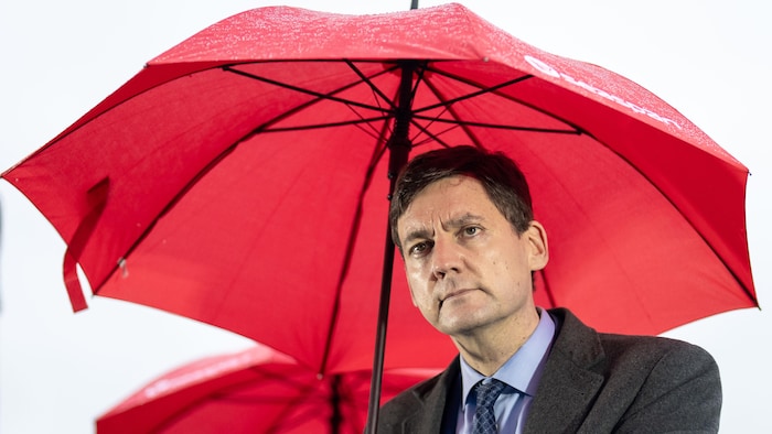 David Eby tient un parapluie lors d'une conférence de presse.