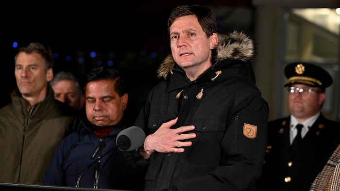 Le premier ministre David Eby aux côtés de deux autres ministres et d'un policier.