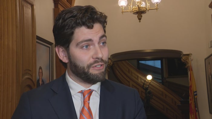 Un homme répond à des questions en mêlée de presse.
