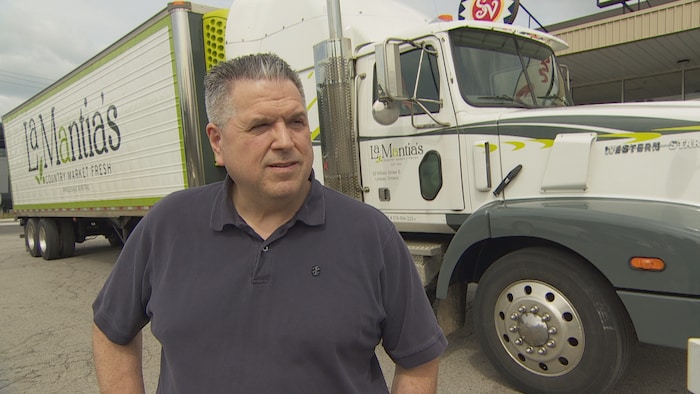Un homme devant un camion de marchandises.