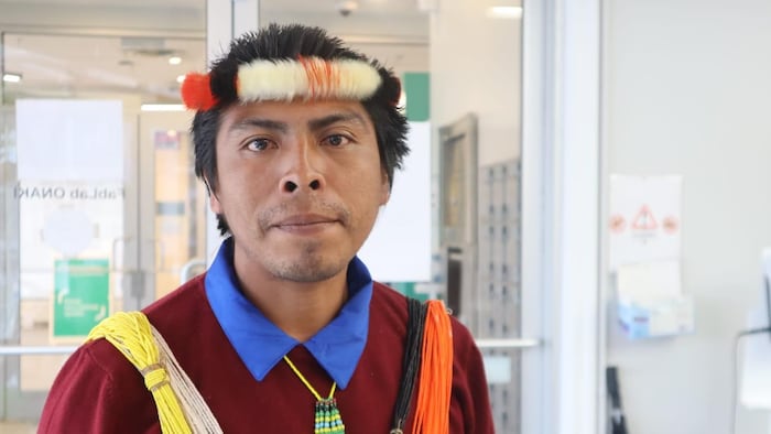 L'homme est vêtu d'habits traditionnels autochtones.