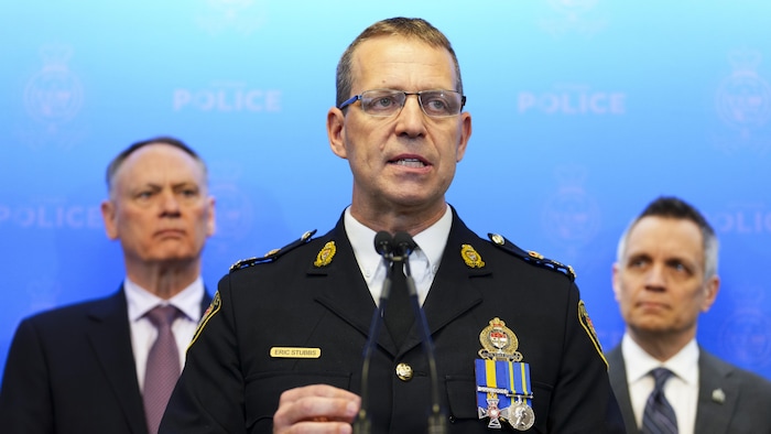 Eric Stubbs en avant-plan lors d'une conférence de presse. Derrière lui, on voit David McGuinty et Mark Sutcliffe.