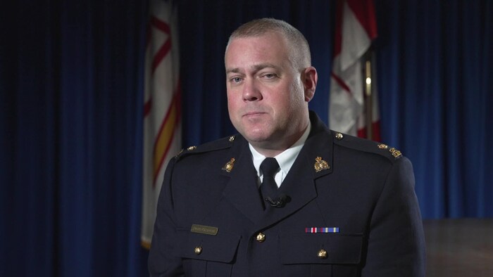 Un membre de la GRC en uniforme est assis, l'air sérieux, determination    une entrevue à la caméra.