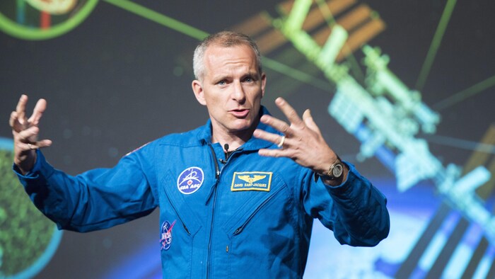 L'astronaute David Saint-Jacques, vêtu de son uniforme à l'effigie de l'Agence spatiale canadienne, donne une conférence qui porte sur son départ vers la Station spatiale internationale.