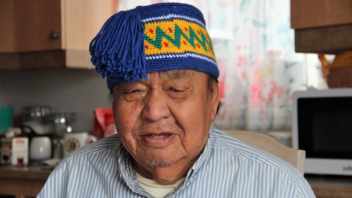 Un homme dans sa cuisine avec un bonnet tricoté sur la tête.