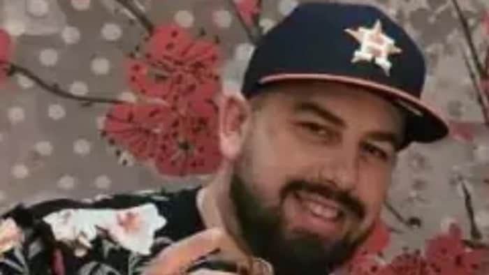 Un homme porte une casquette des Astros de Houston et tient un verre dans la main.