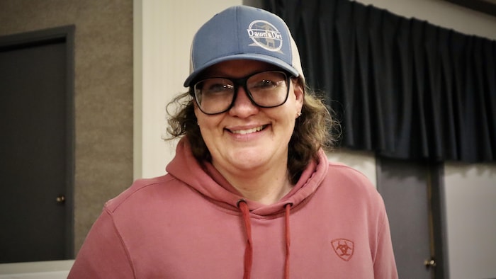 Une femme sourit, une casquette sur la tête.
