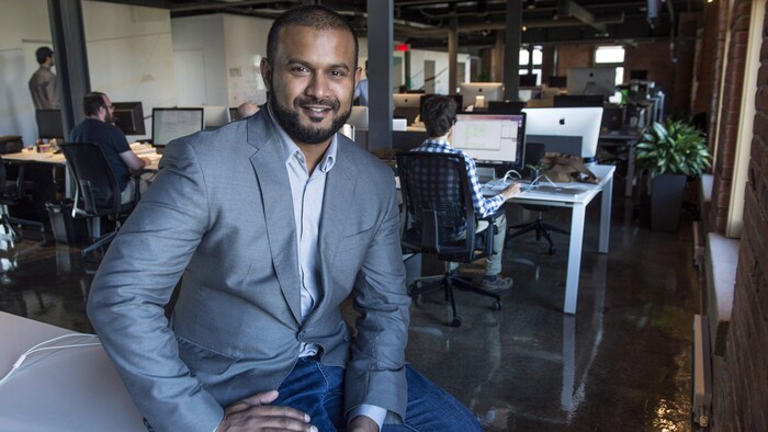 Dax Dasilva, assis sur un bureau dans les locaux de Lightspeed.