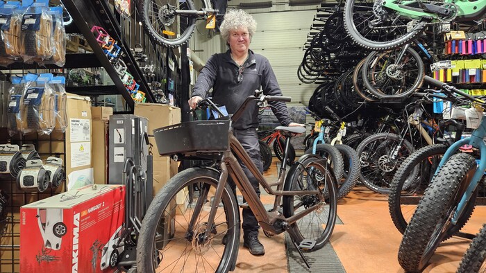 Une personne examine un vélo électrique dans un magasin spécialisé.