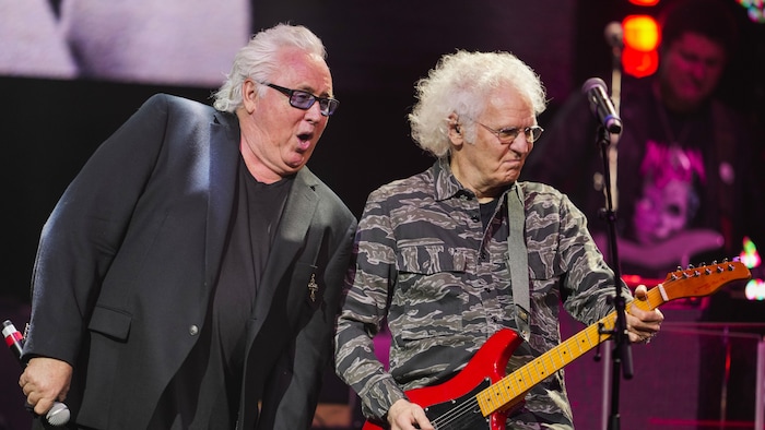 Deux hommes aux cheveux blancs sont sur scène. 