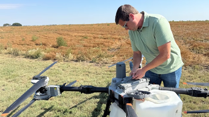 Dean Roberts installe une batterie dans un drone pulvérisateur destiné à être utilisé au-dessus des cultures de sa ferme.