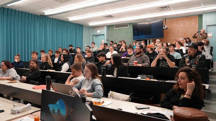 Plusieurs personnes assises dans un amphithéâtre.  