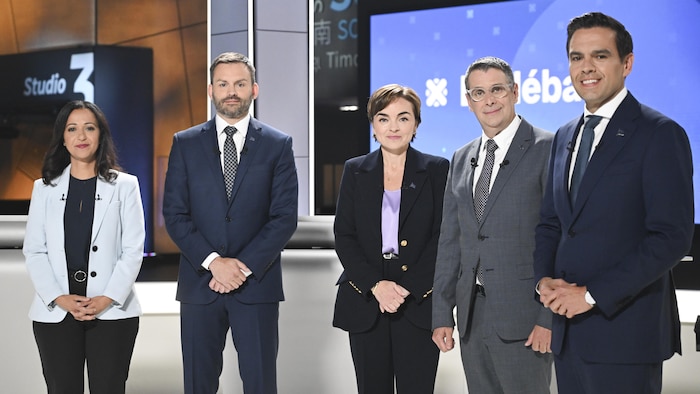 Les chefs des cinq principaux partis politiques du Québec posent debout côte à côte sur un plateau de télévision.