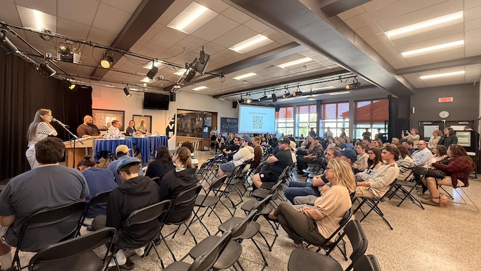 Des étudiants assistent à un débat électoral auquel participent quatre candidats.