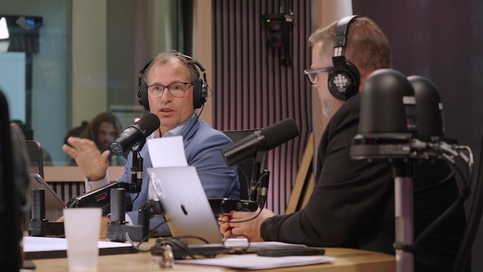 Christian Savard parle alors que le journaliste Étienne Leblanc le regarde, attentif.