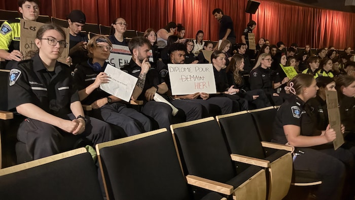 des jeunes ambulanciers assis avec des pancartes