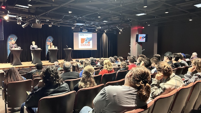 Des gens sont assis dans un auditorium.