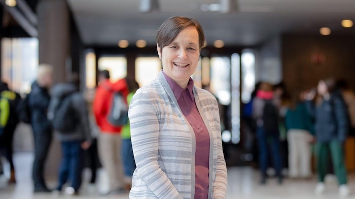 Portrait de Debbie Laliberte Rudman, professeure à la Faculté des sciences de la santé de l'Université Western, debout dans un bâtiment universitaire.