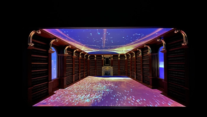 Une maquette de salle de bibliothèque avec des projections de l'univers au plancher, au plafond et dans les fenêtres de chaque côté.