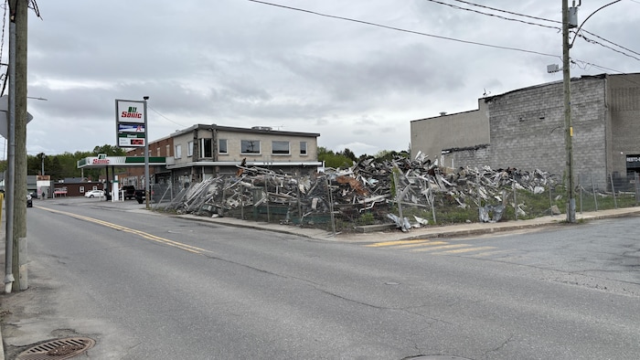 Des débris d'un bâtiment détruit recouvrent un terrain au coin d'une rue.