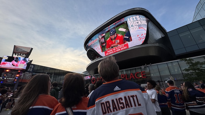 Des partisans de hockey regardent un écran geant 