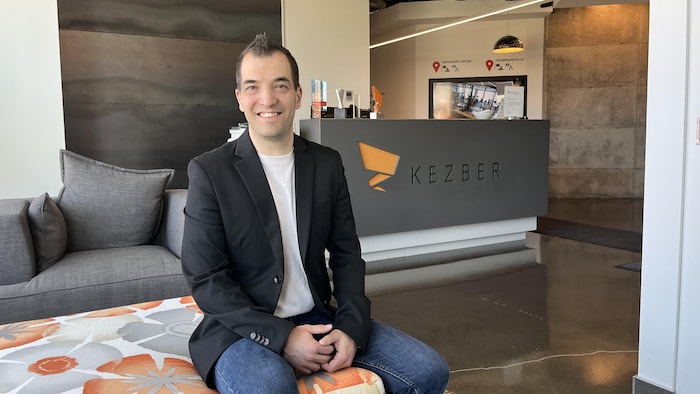 Un homme assis dans un fauteuil dans un vestibule. 