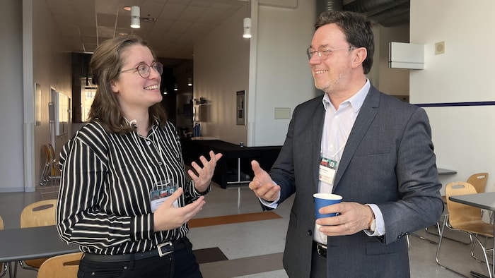 Deux personnes discutent dans un hall. 
