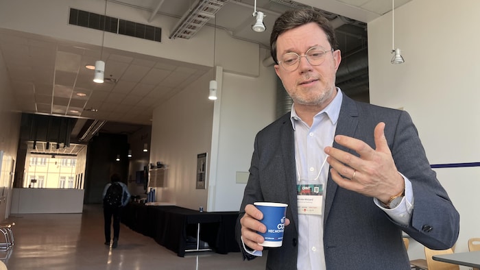 Un homme tient un verre dans un hall. 