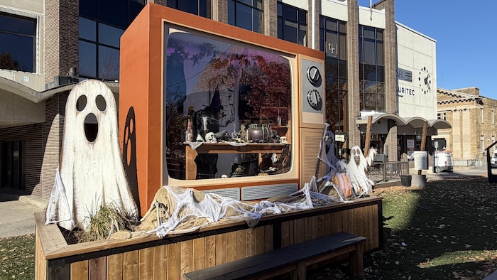 Une vitrine géante en forme de vielle télévision avec une sorcière à l'intérieur et des décors de fantômes autour.